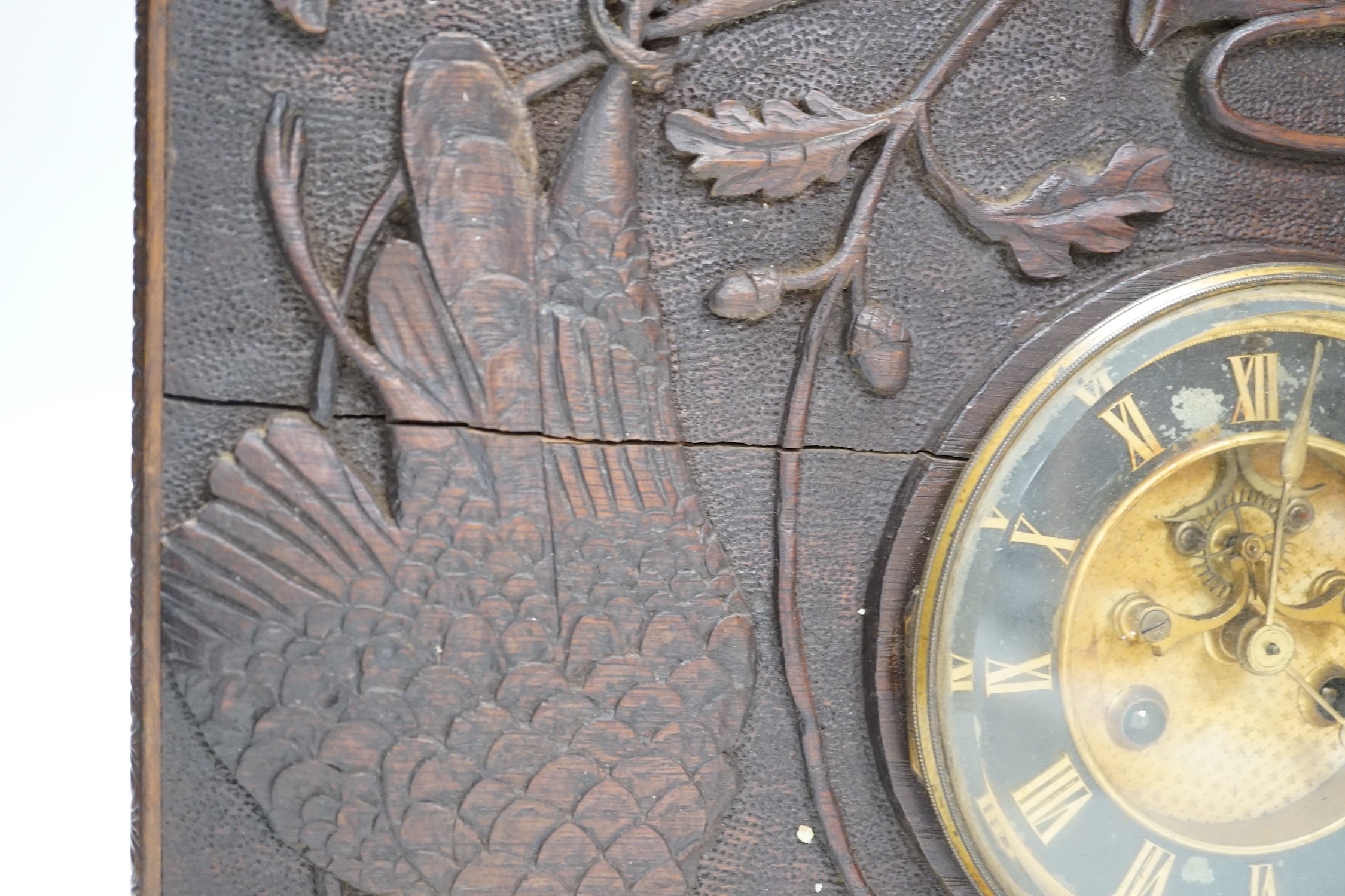 A late 19th century / early 20th century folk art carved oak cased clock, decorated with hanging dead game amongst oak sprigs and acorns, 34x39cm